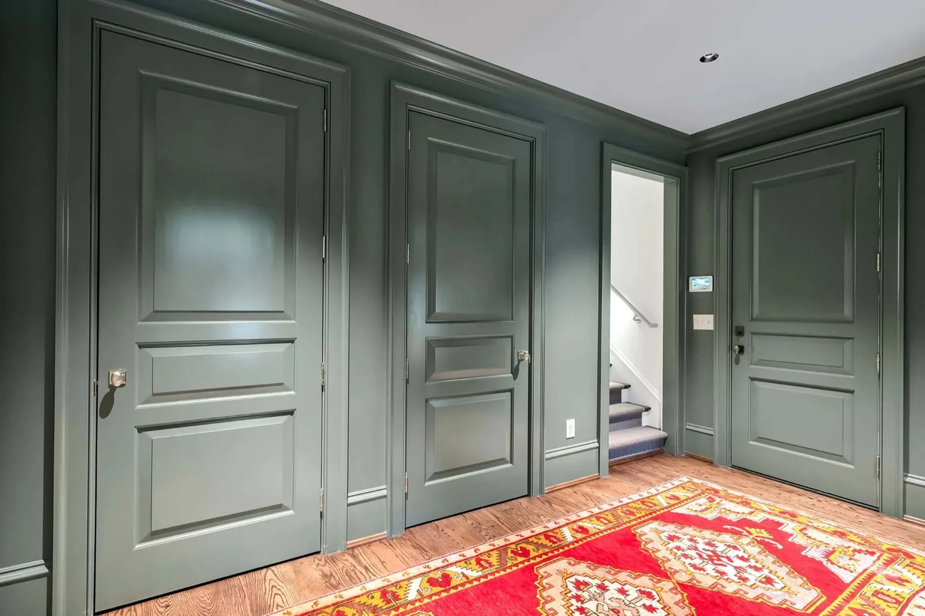 Three painted panel doors set into a matching paneled hallway