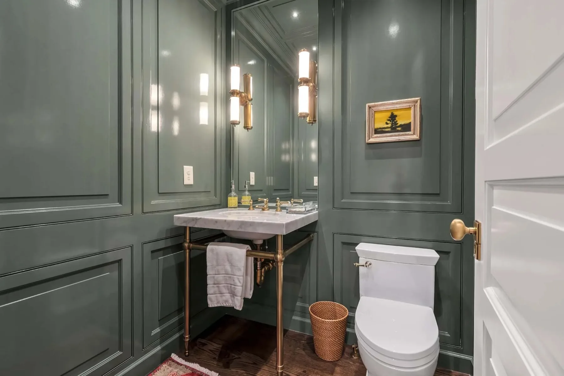 Powder room with full height paneled molding and a marble console sink