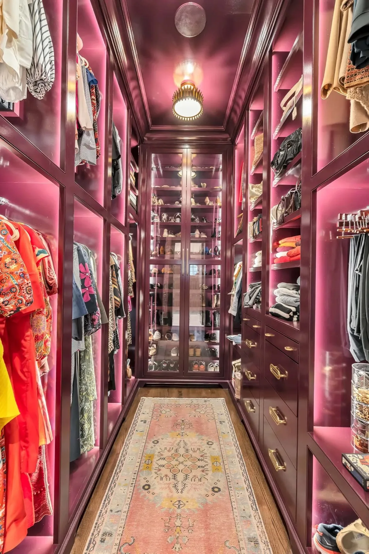 Built-in walk-in closet with glass fronted shelving and brass pulls